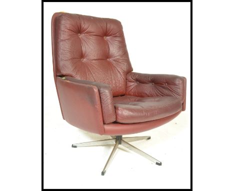 A vintage retro 20th Century button back swivel armchair, upholstered in an oxblood leatherette material raised on a five poi