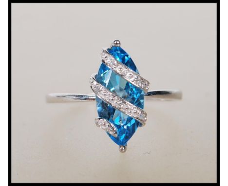 A hallmarked 9ct white gold ring having prong set lozenge shape blue stone with&nbsp;overlapping illusion&nbsp;prongs, set wi