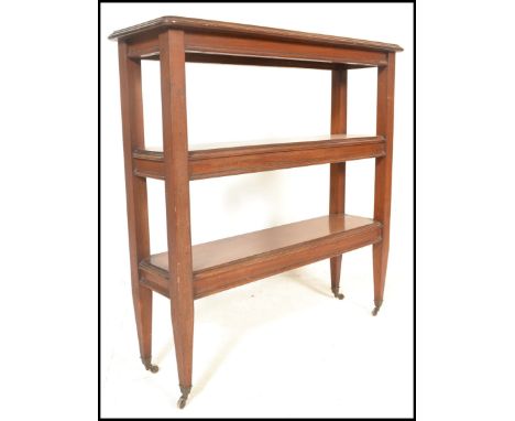 A 19th Century Victorian three tier bookshelf of rectangular form, raised on tapering supports with ceramic castors to the le