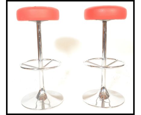 A pair of vintage bar bistro stools raised on central chromed columns terminating in round bases with red leather upholstered