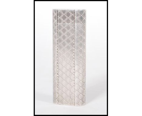 A silver plate lighter by Cartier Paris. The lighter of&nbsp;flattened cylindrical form having engine turned&nbsp;matted deco