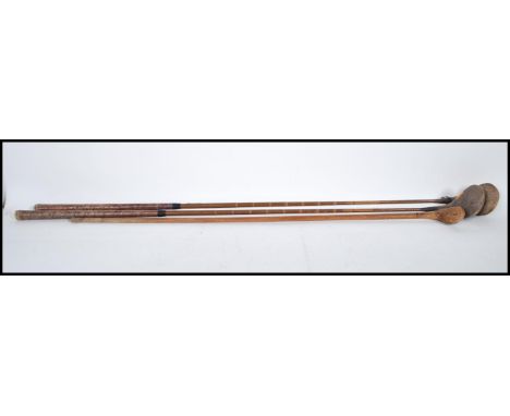 A group of three vintage early 20th Century golf clubs by Auchterlonie having faux cane shafts to include two drivers and a p
