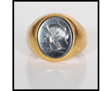 An unmarked 14ct gold signet ring set with an oval black stone to the head engraved with a cameo of a man wearing a helmet. T