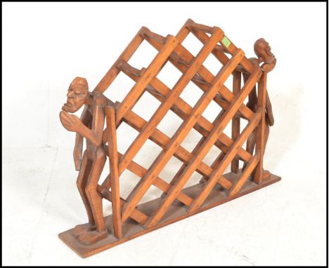 A vintage 20th Century multi section hardwood wine rack mounted on plinth base flanked by a&nbsp; pair of tribal figures to e