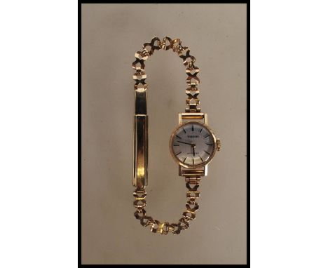 A vintage Tissot Stylist 9ct gold cocktail watch having a cross over design bracelet with a round face with a silvered dial h