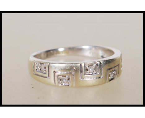 A hallmarked 9ct gold ring set with with five diamonds on a greek key style tapering mount. Hallmarks for Sheffield 375 stamp