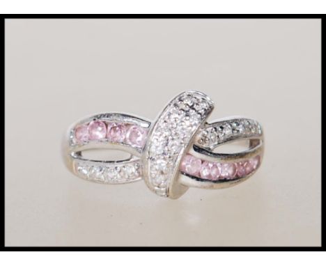 A stamped 375 9ct white gold crossover ring illusion set with white and pink accent stones. Weight 2.2g. Size K.&nbsp;