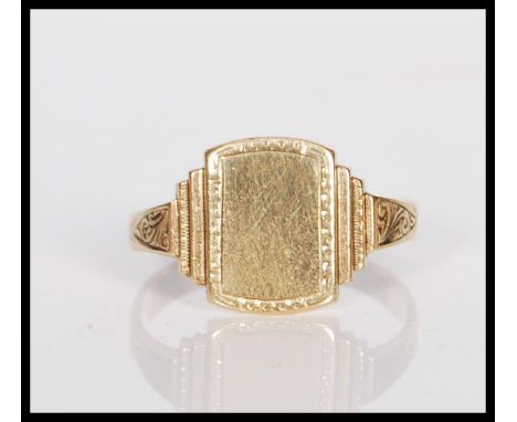 A 9ct gold signet ring having a stepped square head with scrolled decoration shoulders. Marks rubbed but tests as 9ct gold. W