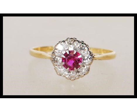 A vintage hallmarked 18ct yellow gold ring set with a central ruby with a halo of diamonds on a decorative pierced mount. App