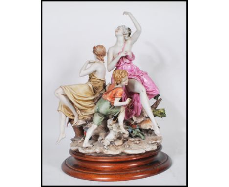 A large Capodimonte ceramic figure group depicting three figures depicting two women in draped clothing a young boy, raised o