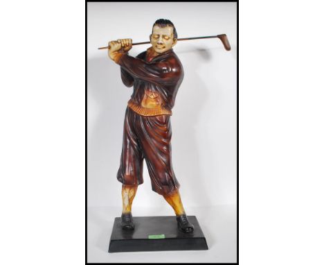 A 20th Century vintage Art Deco style resin figurine in the form of a golfer swinging a club, painted in brown hues and raise