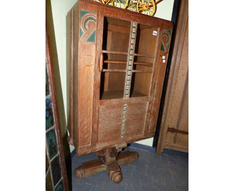 AN INTERESTING ART DECO LIMED AND DECORATED OAK CABINET WITH GLAZED DOOR ON COLUMN SUPPORT AND CRUCIFORM BASE.   60 x 36 x H.