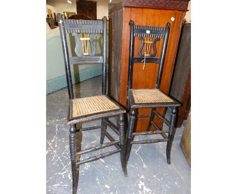 A PAIR OF ANTIQUE EBONISED LYRE BACKED CORRECTION CHAIRS WITH CANED SEATS AND BOBBIN TURNED FRONT LEGS.