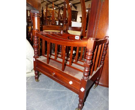 A MAHOGANY CANTERBURY WITH FOUR DIVISIONS AND CENTRAL PIERCED HANDHOLD ON RING TURNED TAPERED LEGS AND BRASS CASTORS.