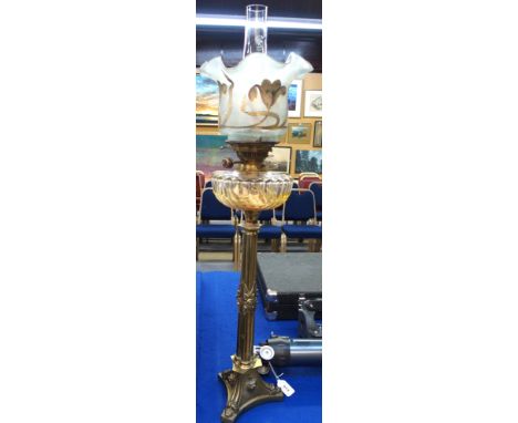 An early 20th Century brass paraffin lamp, with cut glass reservoir and frilled shade, with gilt floral decoration, 86cm high