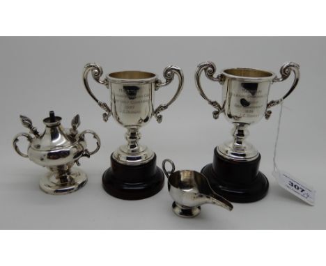 A lot comprising two silver trophy cups (10cm high), London 1926 and 1927, a small white metal oil jug and a white metal tabl