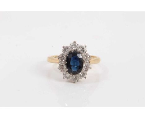 Sapphire and diamond cluster ring with an oval mixed cut blue sapphire, measuring approximately 8mm x 6mm, surrounded by ten 