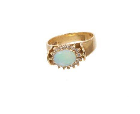 Opal and diamond cluster ring with an oval cabochon opal surrounded by a border of brilliant cut diamonds in 18ct gold settin