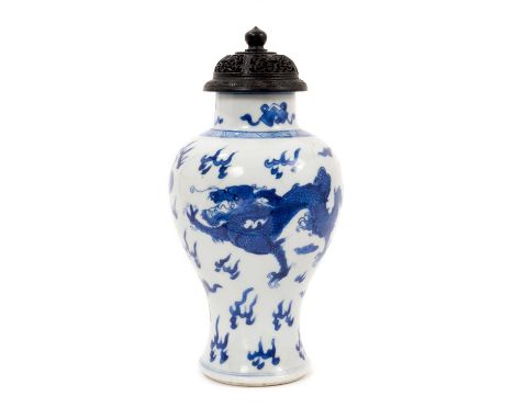 A 19th century Chinese porcelain blue and white baluster shape vase with a carved wooden cover, decorated with a dragon and p