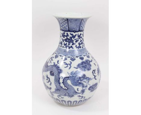An Oriental blue and white vase, Ming style but later, of bottle form with flared rim, decorated with dragons chasing the fla
