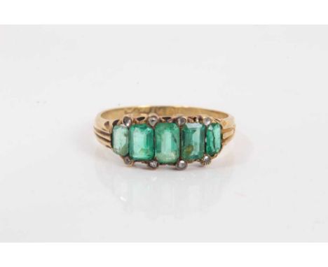 Victorian 18ct gold emerald five stone ring with a line of five graduated step cut emeralds flanked by eight rose cut diamond