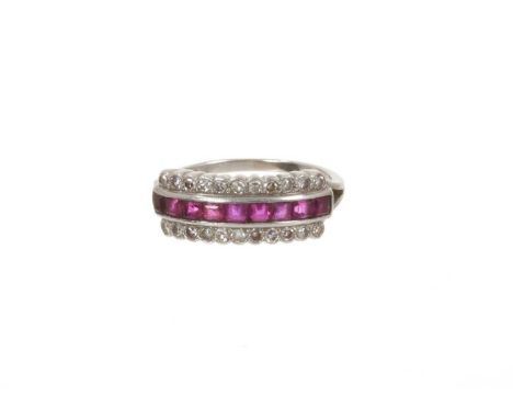 Ruby and diamond ring with a line of nine calibre cut rubies flaked by single cut diamonds in white gold setting with split s