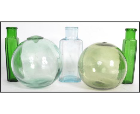 A group of vintage glass wares to include tow green glass fishing buoys with pontil marks and three medicine bottles dating t