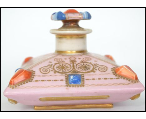 A 19th century Continental ceramic perfume bottle with fitted stopper. In the form of a bejewelled crown having applied gilt 