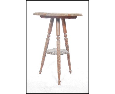 An early 20th century anglo-colonial carved harwood occasional tripod table being raised on turned legs with elephant carved 