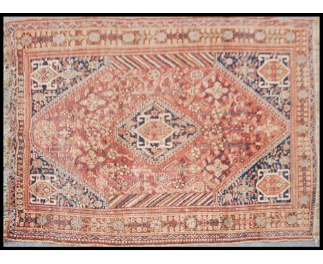 A vintage fine quality handmade tribal carpet rug on a rust background having alternating geometric designs. Measures 155cms 