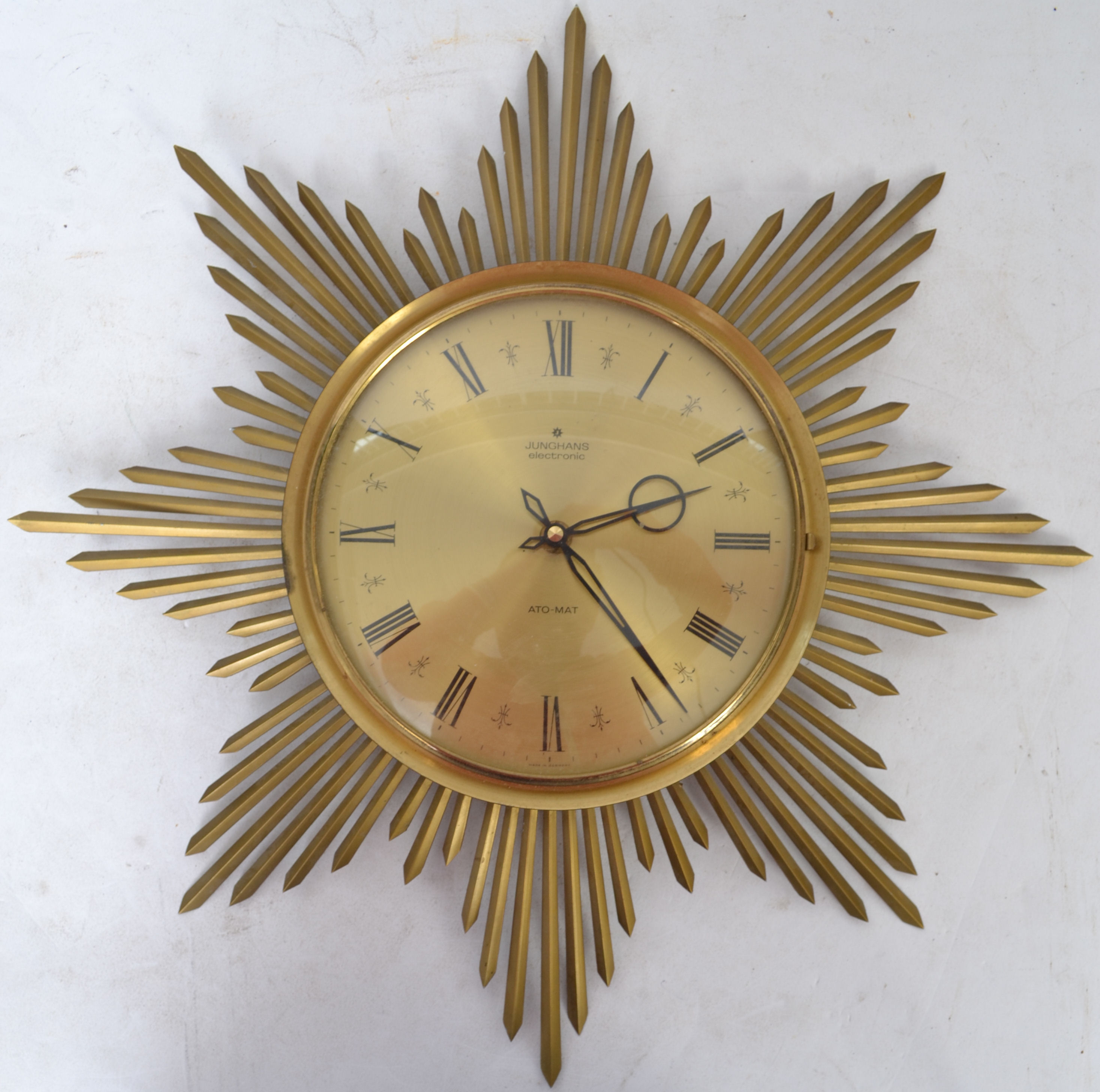 A 1950's retro starburst wall clock by Junghans AtoMat in brass with