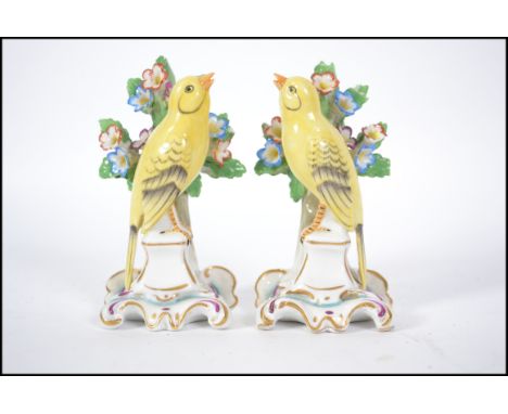 A true pair of 20th century believed Dresden / Meissen ceramic canaries on pedestal bases in front of a floral spray. Marked 