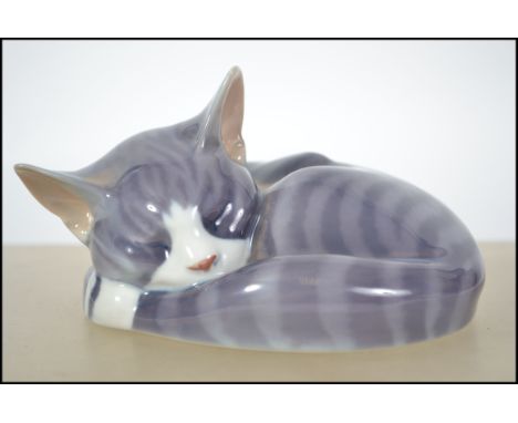 A Royal Copenhagen ceramic sleeping cat figurine 057 along with a Royal Doulton Images Of Nature cat figurine. Measures 14cms