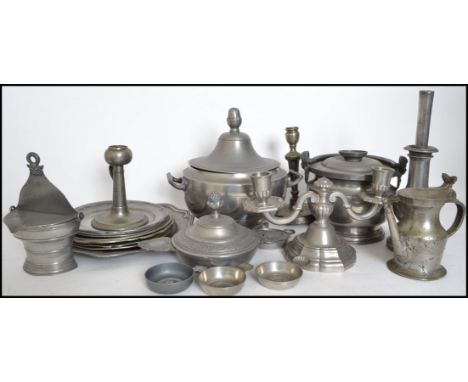 A large collection of pewter to include plates of varying sizes, twin handled bowl, cauldron, taste de vin's, pots, candelabr