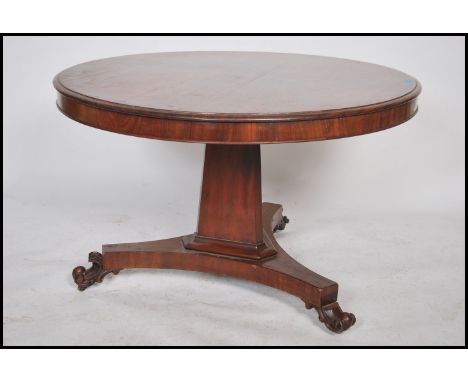 A Victorian mahogany tilt top circular breakfast / loo dining table being raised on a tripod base with inverted tapering colu