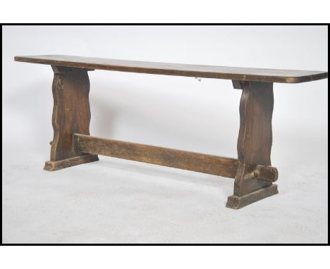 An early 20th century solid oak peg jointed pig refectory bench having a planked top with lyre shaped peg jointed supports wi