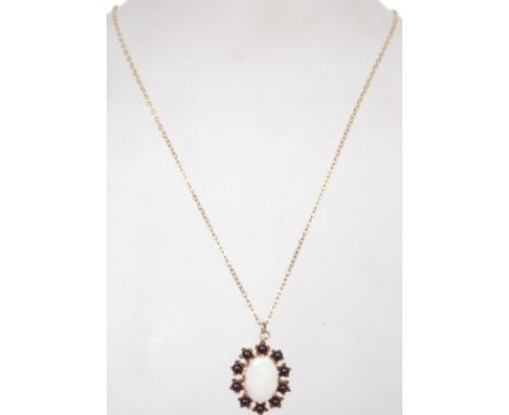 A 9ct gold and and red stone pendant and necklace combination. The oval cut opal surrounded by ball red stones. Hallmarked fo
