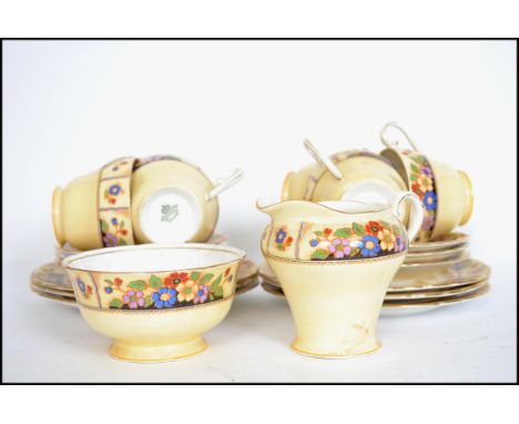 An Aynsley 6 person art deco tea service in a chintzy pattern on a cream background consisting of cups, saucers, side plates,