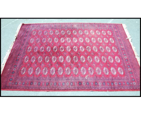 A vintage 20th century Afghan carpet rug of woollen construction having red ground with geometric design. Measures 114cms x 7