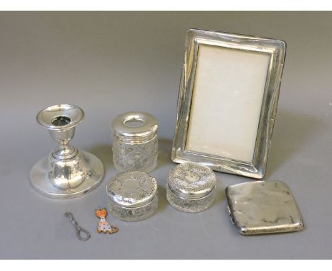 Assorted silver, comprising a candlestick, three silver topped dressing table jars, a photograph frame, and a cigarette case