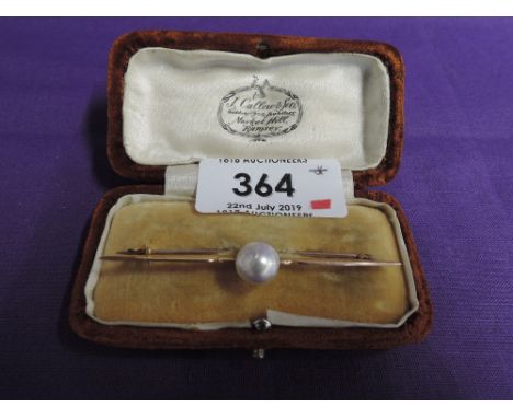A yellow metal bar brooch stamped 9ct having a central baroque pearl 