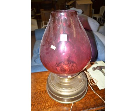 A large late 19th Century brass table oil lamp, with circular brass reservoir base, large cranberry glass shade (later conver
