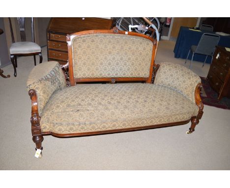 A Victorian walnut salon settee, the back and arms carved and pierced with floral decoration and upholstered with foliate mat