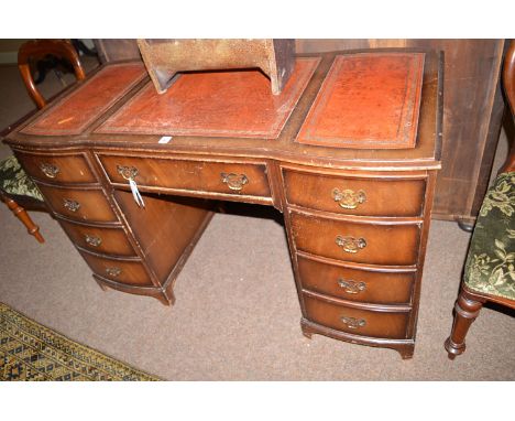 A reproduction mahogany kneehole desk, fitted centre drawer and four small drawers either side, raised on bracket feet (in di