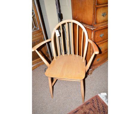 An Ercol Windsor style elbow chair with spindle back and shaped arms, the solid elm seat raised on turned legs joined by stre