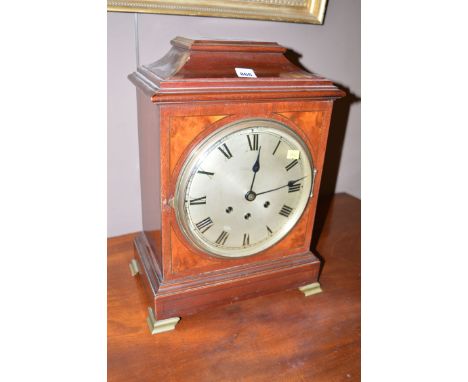 An early 20th Century mahogany cased mantel clock, the silvered roman dial within bezel inlaid with figured walnut corners an
