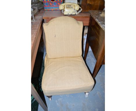 A lady's Victorian nursing chair with shaped back, the back and seat covered in a mustard coloured loose cover, raised on tur