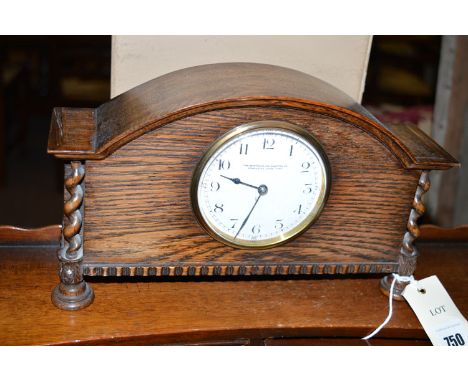 An oak cased mantel clock with spiral twist decoration and enamel dial, by The Northern Goldsmiths, Newcastle upon Tyne.