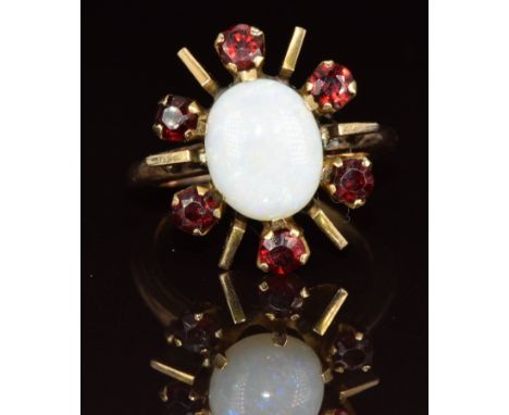 A 9ct gold ring set with an oval opal cabochon surrounded by garnets, 6.4g, size O