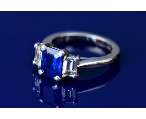 A platinum ring set with an emerald cut sapphire of approximately 1.8ct and two emerald cut diamonds each approximately 0.35c